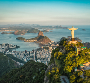 Panoramablick auf Rio de Janeiro mit der Christusstatue auf dem Corcovado, der Zuckerhut im Hintergrund und die Stadt an der Küste mit Buchten und Bergen.