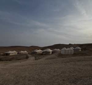 Zeltlager in der Wüste bei Marrakesch, umgeben von sandigen Hügeln unter bewölktem Himmel.