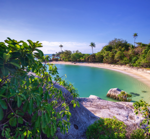 Abgeschiedene Bucht mit Sandstrand, türkisfarbenem Wasser, Felsen und tropischer Vegetation auf der Insel Bintan in Indonesien.
