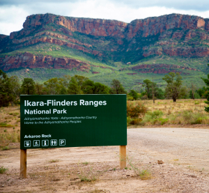 Schild des Ikara-Flinders-Ranges-Nationalparks vor Berglandschaft in Australien.