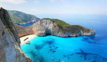 Panoramablick auf die berühmte Navagio-Bucht auf Zakynthos mit weißem Sandstrand, türkisem Wasser und umgebenden Steilklippen.