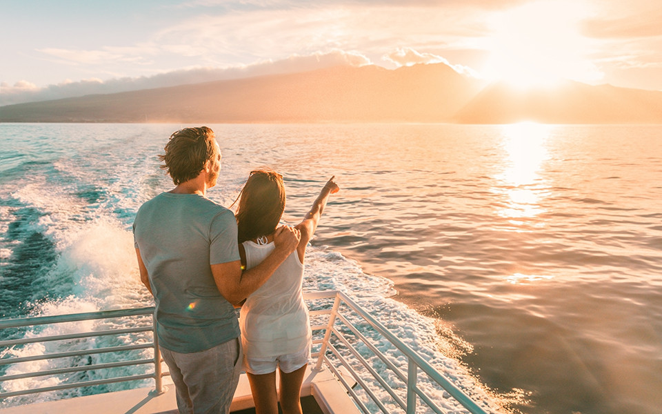Paar an Deck eines Kreuzfahrtschiffes genießt den Sonnenuntergang 
