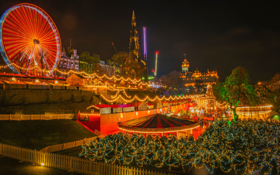 Festlich beleuchtetes Edinburgh Winter Festival mit funkelnden Lichterketten, einem leuchtenden Riesenrad und stimmungsvoller Weihnachtsmarkt-Atmosphäre in der historischen Altstadt.