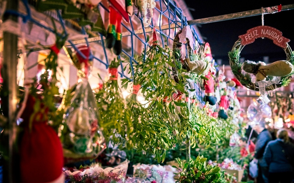 Weihnachtsmarkt auf Madeira mit festlich dekorierten Ständen, Mistelzweigen und traditionellen Handwerkskunst, umgeben von stimmungsvollen Lichtern und fröhlicher Atmosphäre.