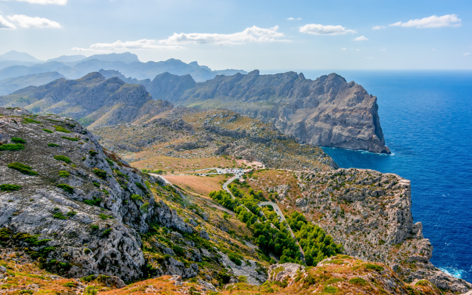 Mallorca Ausflugstipp: Berglandschaft der Serra de Tramuntana auf Mallorca mit zerklüfteten Felsen, grünen Tälern und spektakulärem Blick auf das tiefblaue Meer.