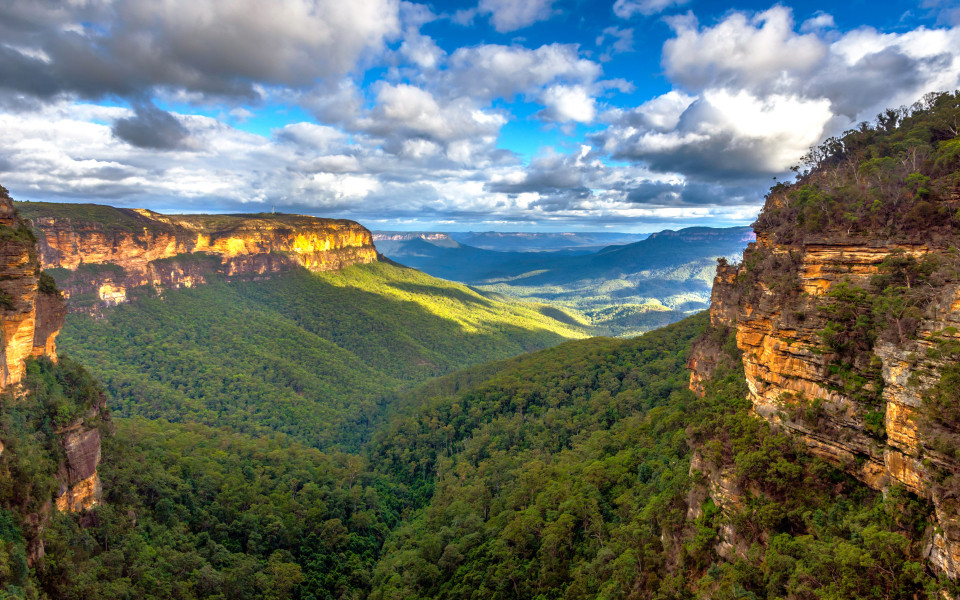Blick auf die Blue Mountains, Australien, mit tiefen Tälern und steilen Felsen, umgeben von grünen Wäldern.