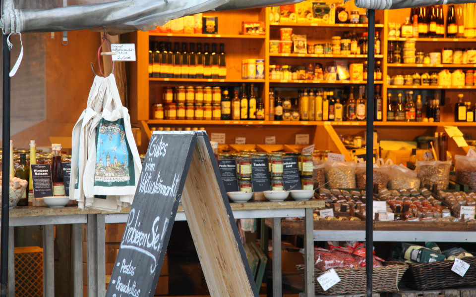 Gemütlicher Marktstand auf dem Viktualienmarkt in München mit regionalen Spezialitäten, handgemachten Delikatessen und traditioneller Marktatmosphäre.