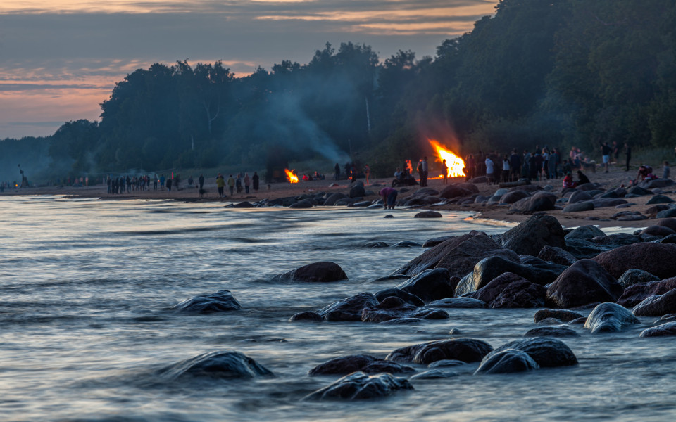 Menschen feiern die Johannisnacht mit großen Lagerfeuern am Sandstrand der Ostsee