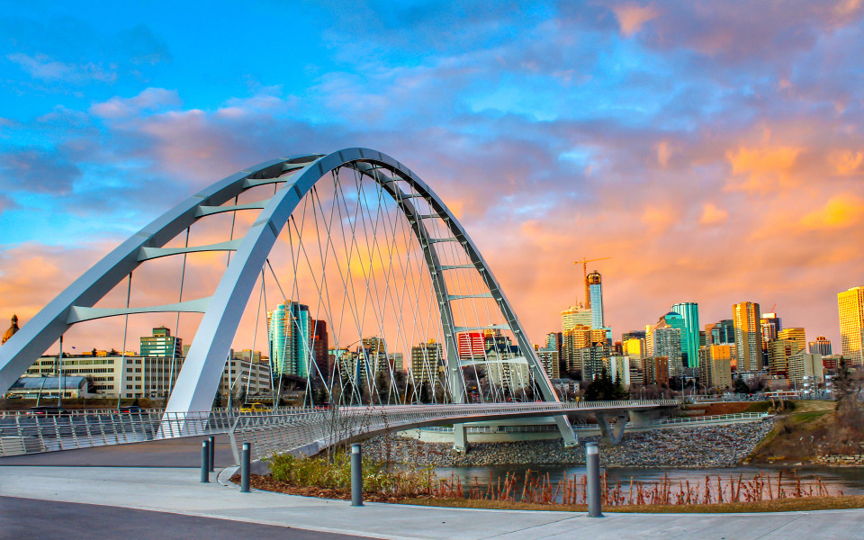 Moderne Bogenbrücke mit Blick auf die Skyline von Edmonton bei Sonnenuntergang.