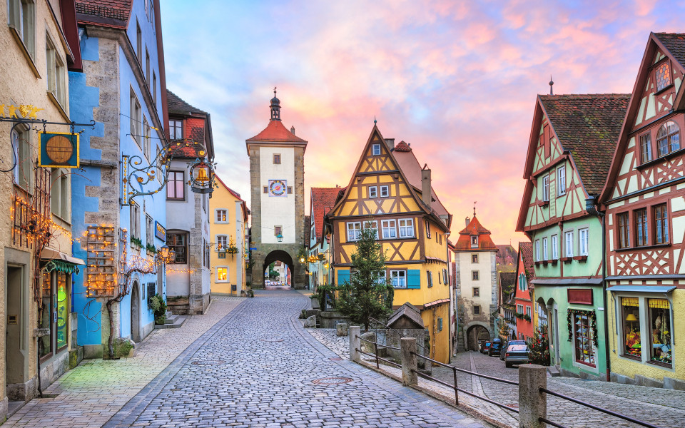 Historische Altstadt mit Fachwerkhäusern und gepflasterter Straße in Rothenburg ob der Tauber, Deutschland, bei Sonnenuntergang.