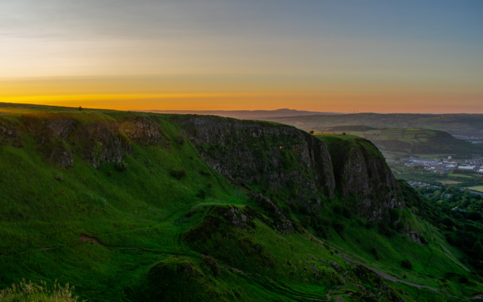Luftaufnahme eines farbenfrohen Sonnenuntergangs im Cave Hill Country Park Belfast mit Stadt und Hügel 