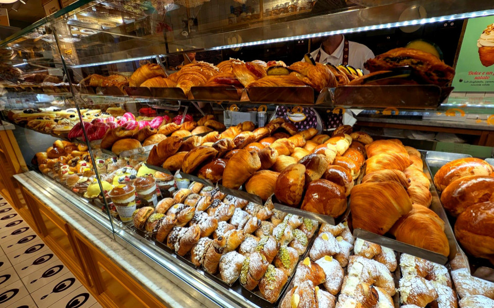 Auslage einer Pasticceria in Neapel mit gefüllten Cornetti, Sfogliatelle, Gebäck mit Puderzucker und weiteren italienischen Süßspeisen.