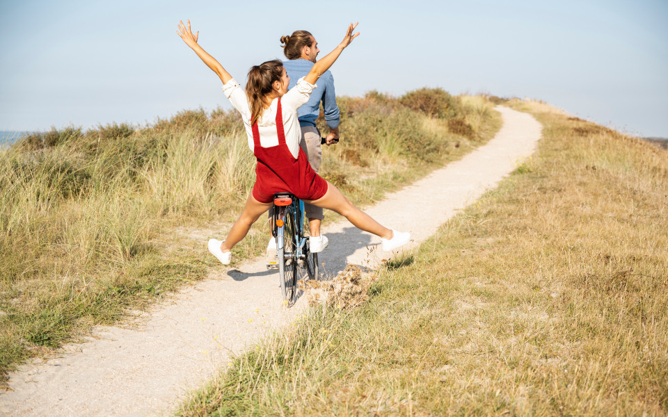 Unbeschwerte Freundin genießt Fahrradtour mit Freund an einem sonnigen Tag